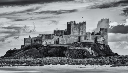 Buildings by sea against cloudy sky