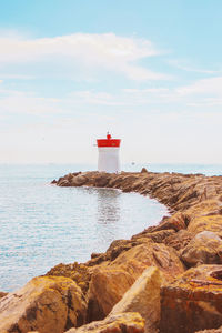 Lighthouse by sea against sky