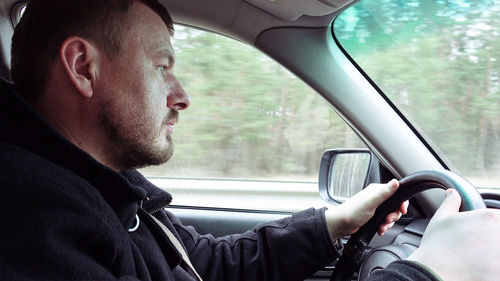 Side view of man sitting in car