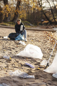 Male environmentalist picking up plastics littered on sand