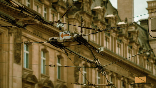 Low angle view of power lines against buildings