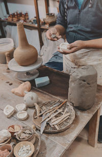 Man molding clay to make ceramics with his hands, artisan working in his workshop, selective focus