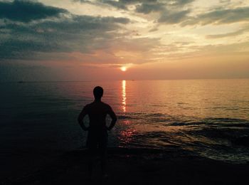 Silhouette of people standing on beach at sunset