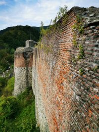 Stone wall by old building against sky