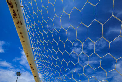 Low angle view of fence against blue sky