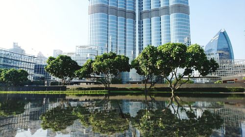 Reflection of trees and buildings in lake against sky