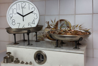 Clock and currency on weight scale against wall
