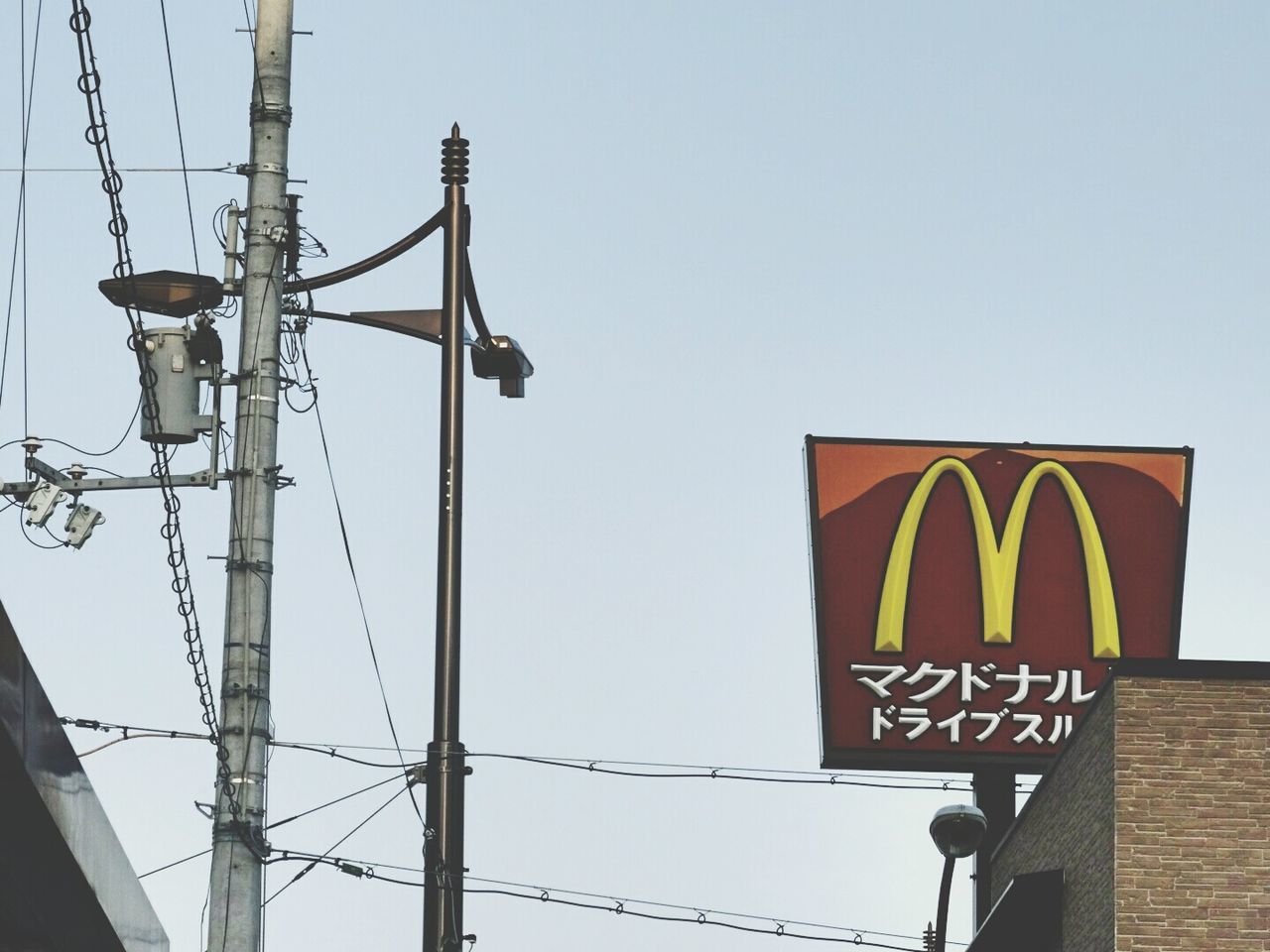 low angle view, clear sky, communication, text, western script, copy space, sign, information sign, guidance, pole, cable, yellow, information, electricity, power line, blue, capital letter, outdoors, sky, day