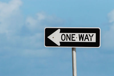 Low angle view of road sign against blue sky