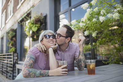 Young couple sitting in outdoor cafe drinking ice tea