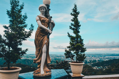 Statue by potted plants against sky