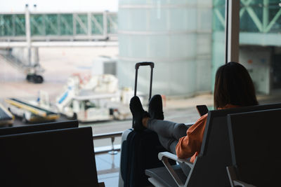 Woman checks her mobile phone while waiting for her flight at the airport.