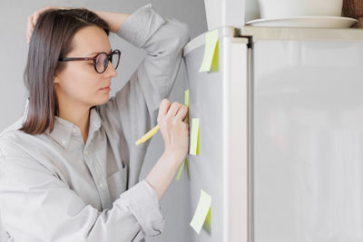 Woman writing on sticky note