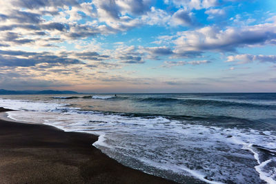 Scenic view of sea with crashing waves against dramatic sky during sunrise