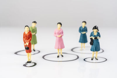 Individual miniature female models isolated inside circles drawn on a white surface