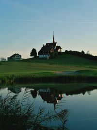 Scenic view of calm lake with houses in background