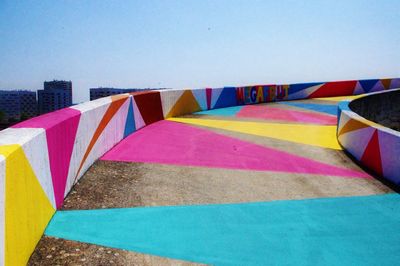 Close-up of multi colored umbrellas against blue sky