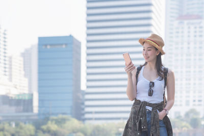 Young woman wearing hat standing against built structure