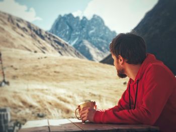 Side view of young man sitting on mountain
