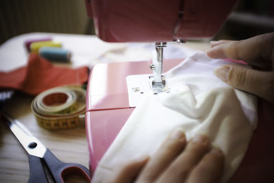 Cropped hand of woman using sewing machine