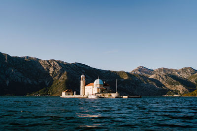 Scenic view of sea and mountains against clear blue sky