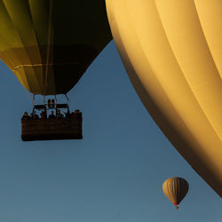 Low angle view of hot air balloons flying against clear sky