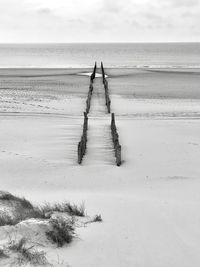 Wooden posts on beach against sky