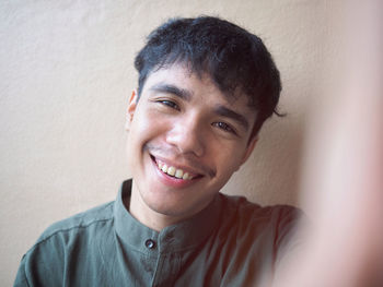 Portrait of smiling young man against wall