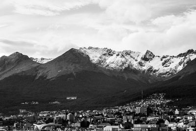 Aerial view of city by snowcapped mountains against sky