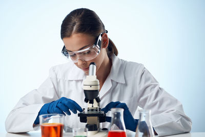 Girl using microscope against blue background