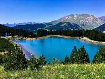 Scenic view of lake and mountains against clear blue sky