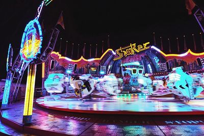 Illuminated carousel in amusement park at night