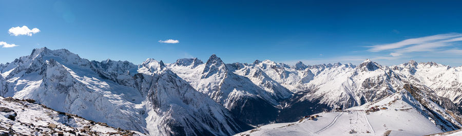 Panoramic view of winter snowy mountains in caucasus region in russia with blue sky