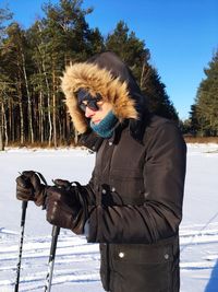 Young woman standing on snow covered tree against clear sky