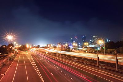 Light trails on city street against sky at night