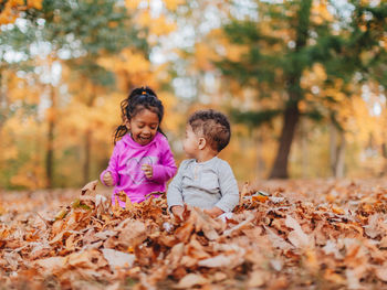 Siblings standing on leaves during autumn