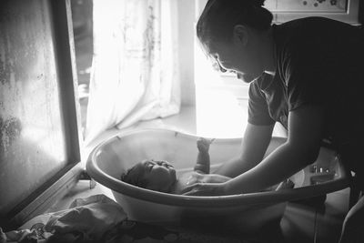 Mother bathing son in bathtub at home