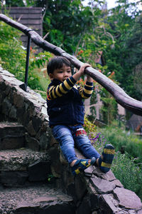 Full length of boy sitting on rock