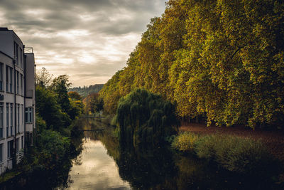 Canal amidst trees and buildings against sky