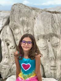 Portrait of smiling girl sitting against carvings on rock