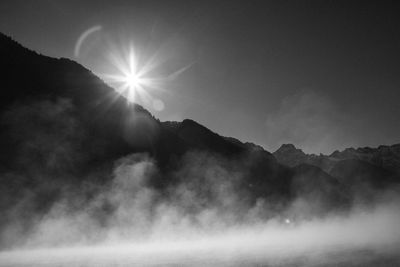 Scenic view of silhouette mountains against bright sun