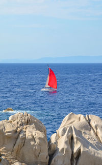 Sailboat on rock by sea against sky