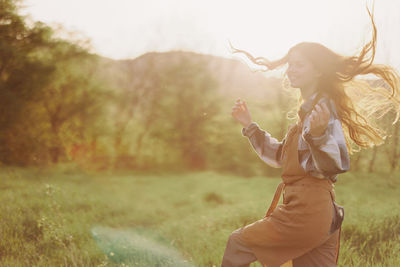 Young woman with arms raised standing on field