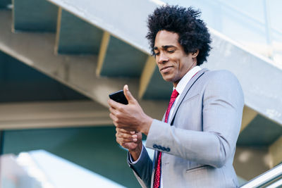 Smiling businessman holding smart phone outdoors