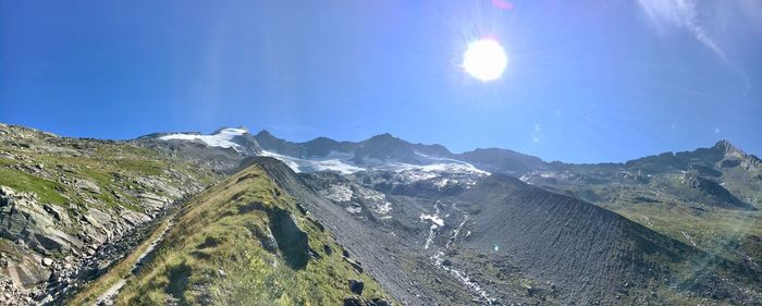 Scenic view of snowcapped mountains against blue sky on sunny day