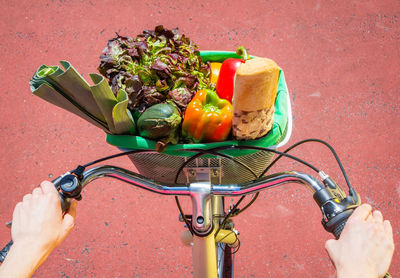 Cropped image of woman with bicycle and vegetables in basket on street