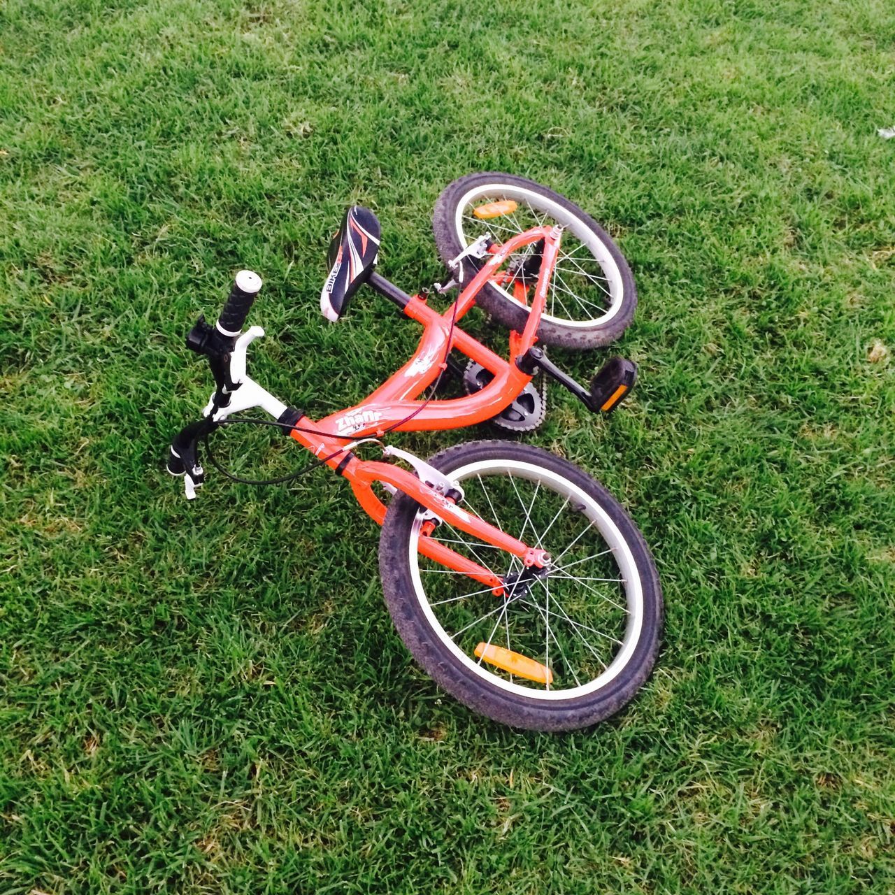 grass, bicycle, grassy, green color, field, lawn, high angle view, no people, day, transportation, outdoors, park - man made space, wheel, land vehicle, growth, childhood, metal, absence, sunlight, plant