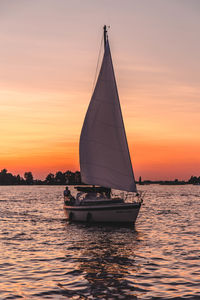 Sailboat sailing on sea against sky during sunset