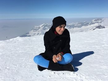 Girl sitting on snow covered landscape