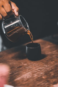 Close-up of hand pouring coffee in cup